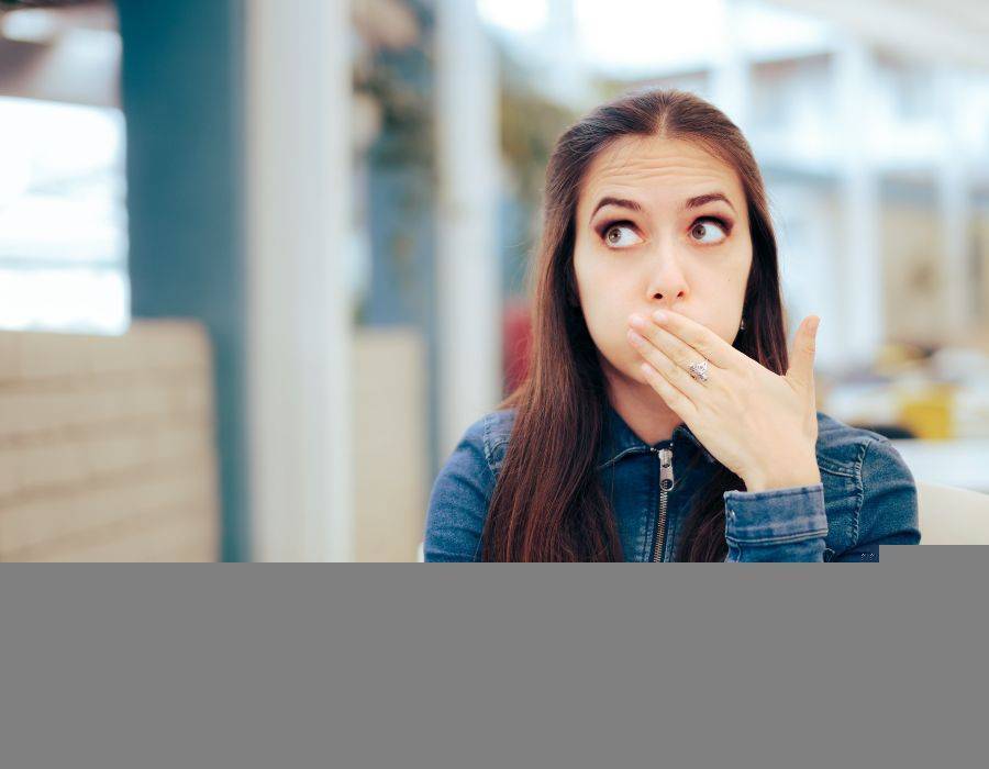 Person experiencing hiccups, covering their mouth in surprise