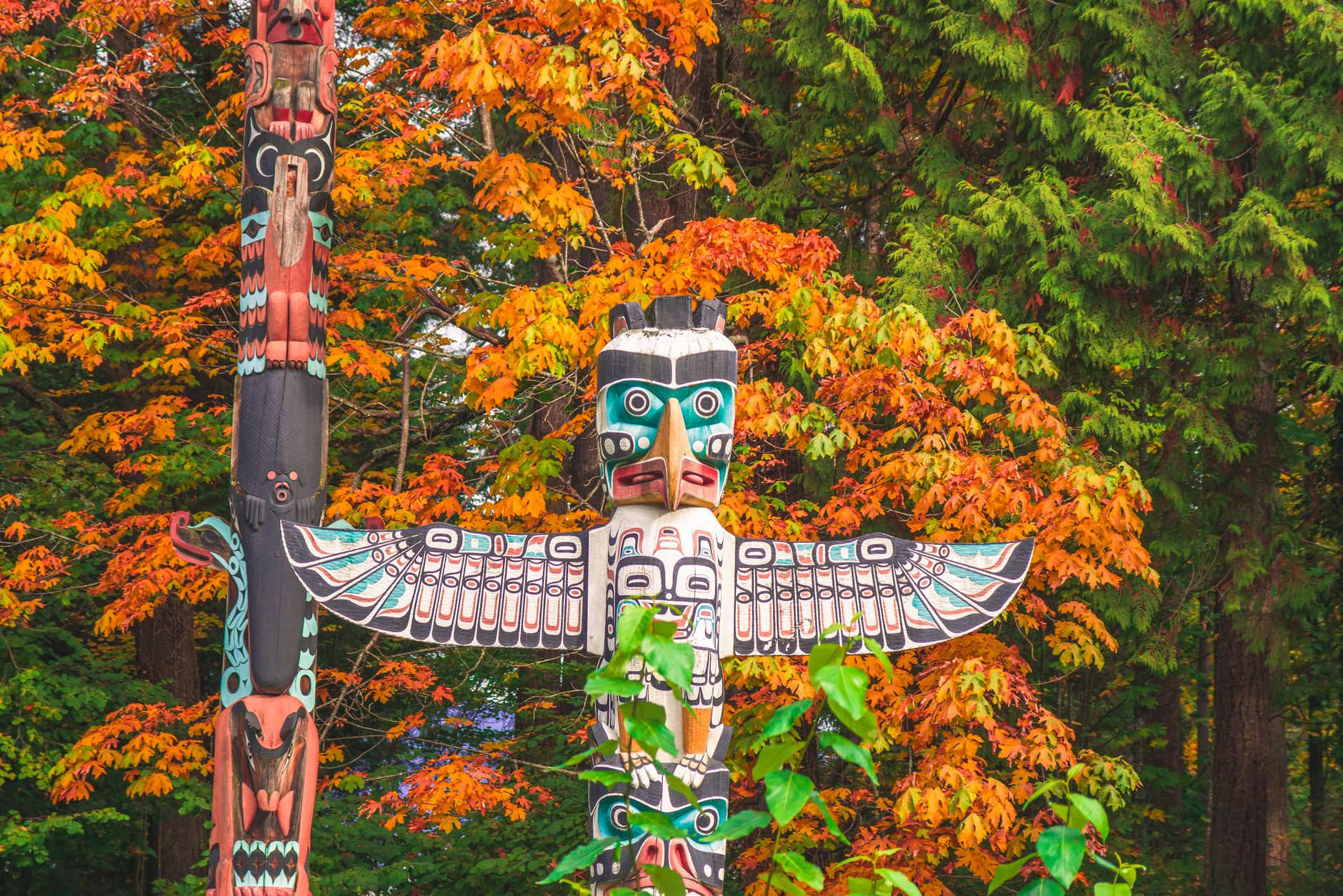 Four carved wooden masks or totem poles representing different animals arranged together.