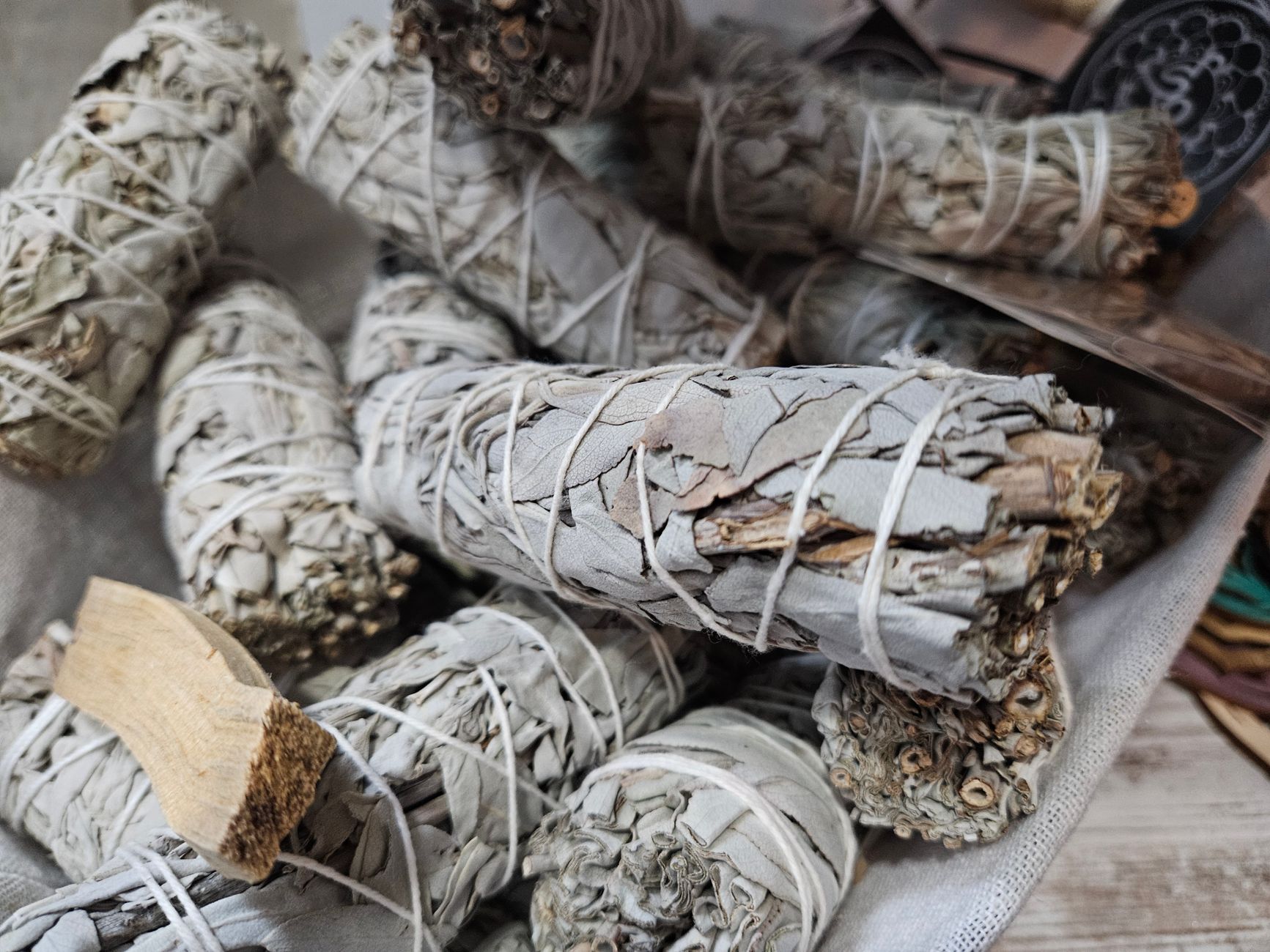 Traditional woven bundle containing sacred feathers, dried plants, and ceremonial objects arranged on dark fabric.