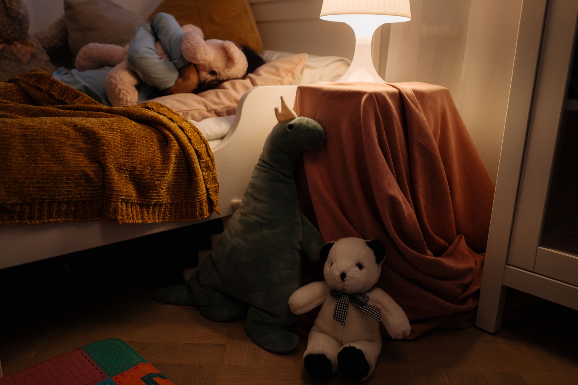 A child sleeping peacefully in bed while candlelight flickers softly on the bedroom wall.
